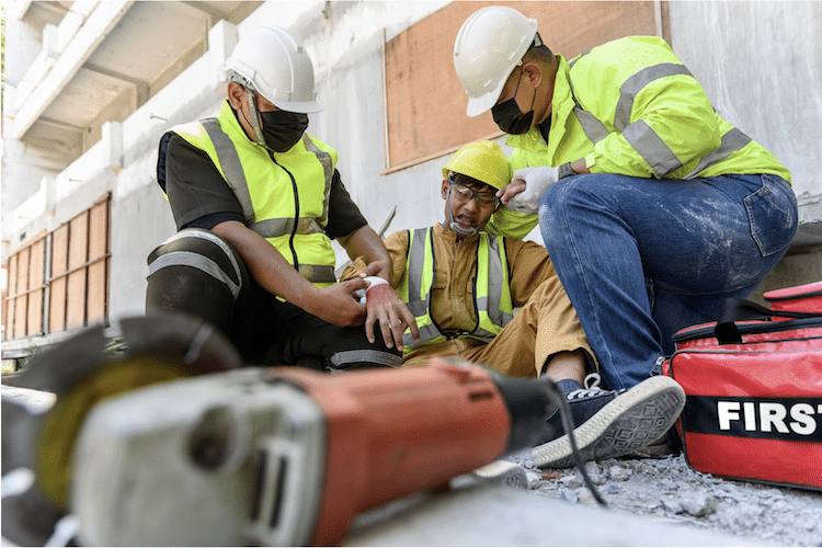 first aid being administered to a construction worker on the ground due to heat related illness from physical activity and high temperature on the job site