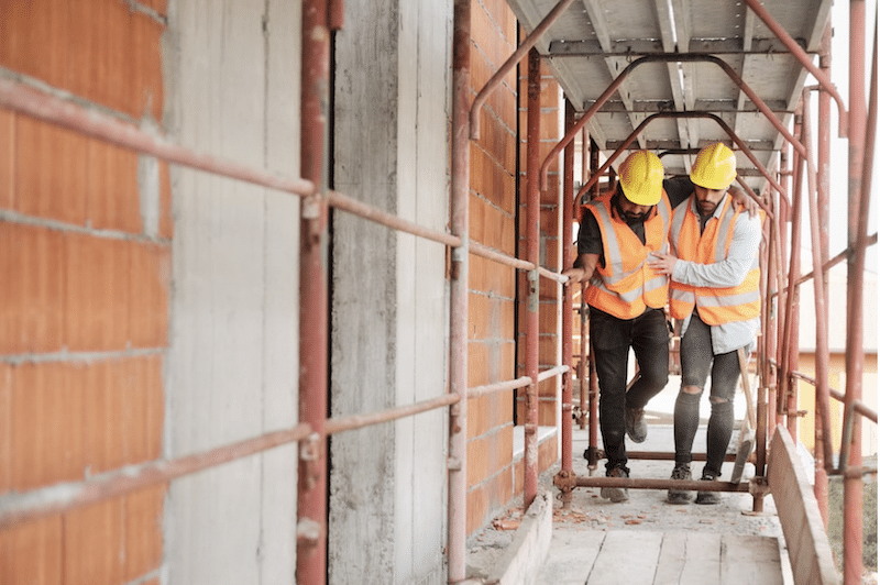 construction worker helping injured colleague on construction Site after a project risk or safety risk issue